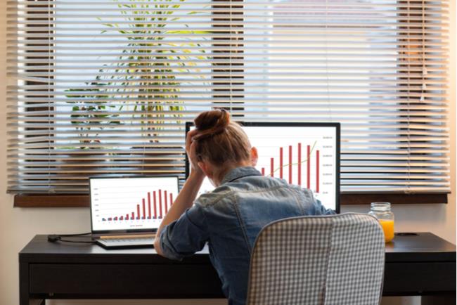 אישה צעירה יושבת חסרת אונים מול מסכי המחשב במשרד, סובלת מדיכאון עבודה